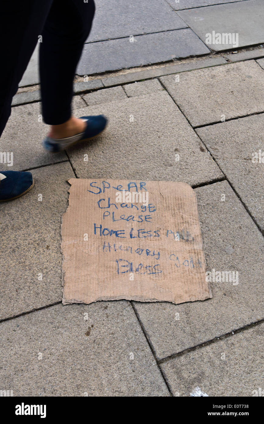 Piedini femmina passo passato un senzatetto Beggar's sign. Foto Stock