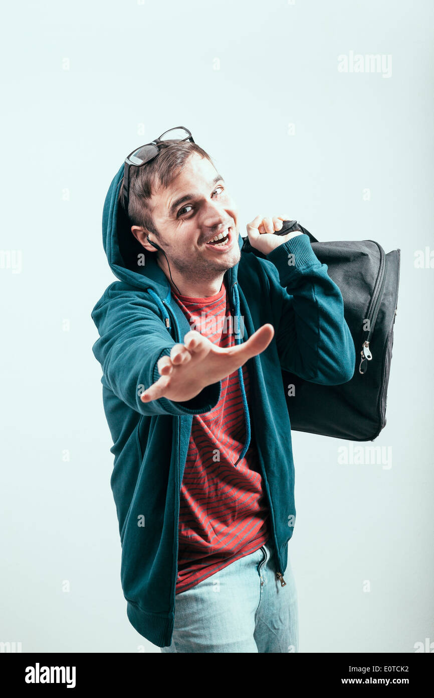 Uomo estatica nel hoodie viaggia con bagagli. Foto Stock