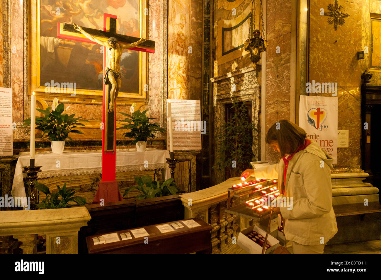 Una donna di accendere una candela nella chiesa cattolica di Santa Maria Maddalena ( Santa Maria Maddalena ), Roma, Italia Europa Foto Stock