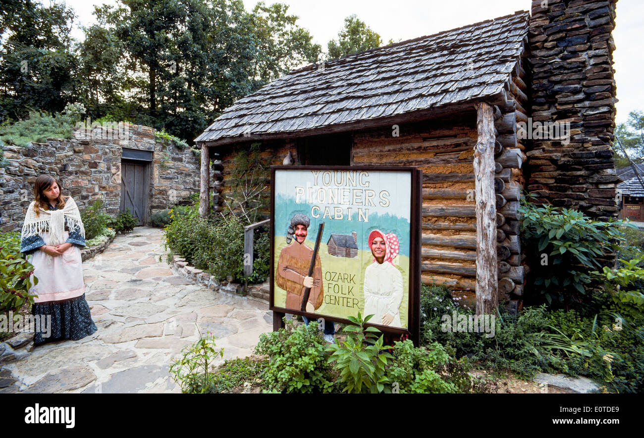 Una guida attende mentre due visitatori pongono dietro la foto ritagliata a segno i giovani pionieri cabina a Ozark Centro Folk, un parco statale in Arkansas, STATI UNITI D'AMERICA Foto Stock