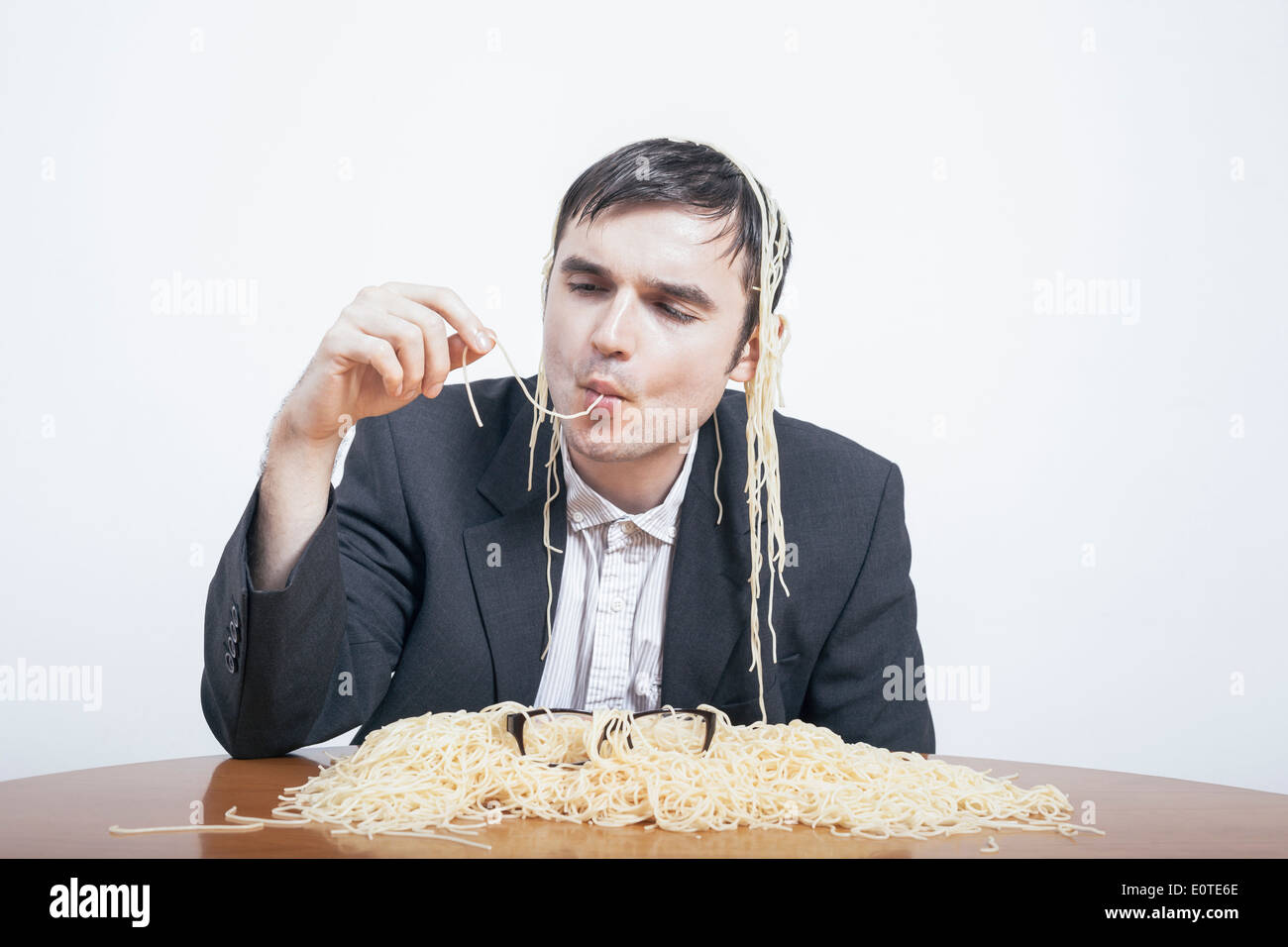 Indulgenza e il consumismo concetto. Imprenditore golosa mangiare pasta. Foto Stock