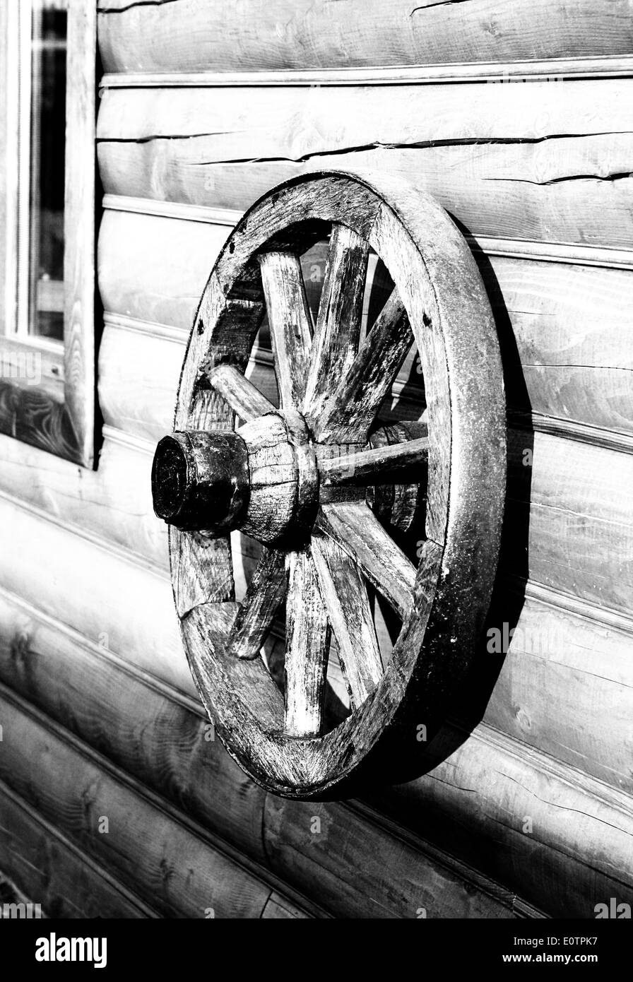 La vecchia ruota in legno da un carrello si blocca su una parete da registri naturale Foto Stock