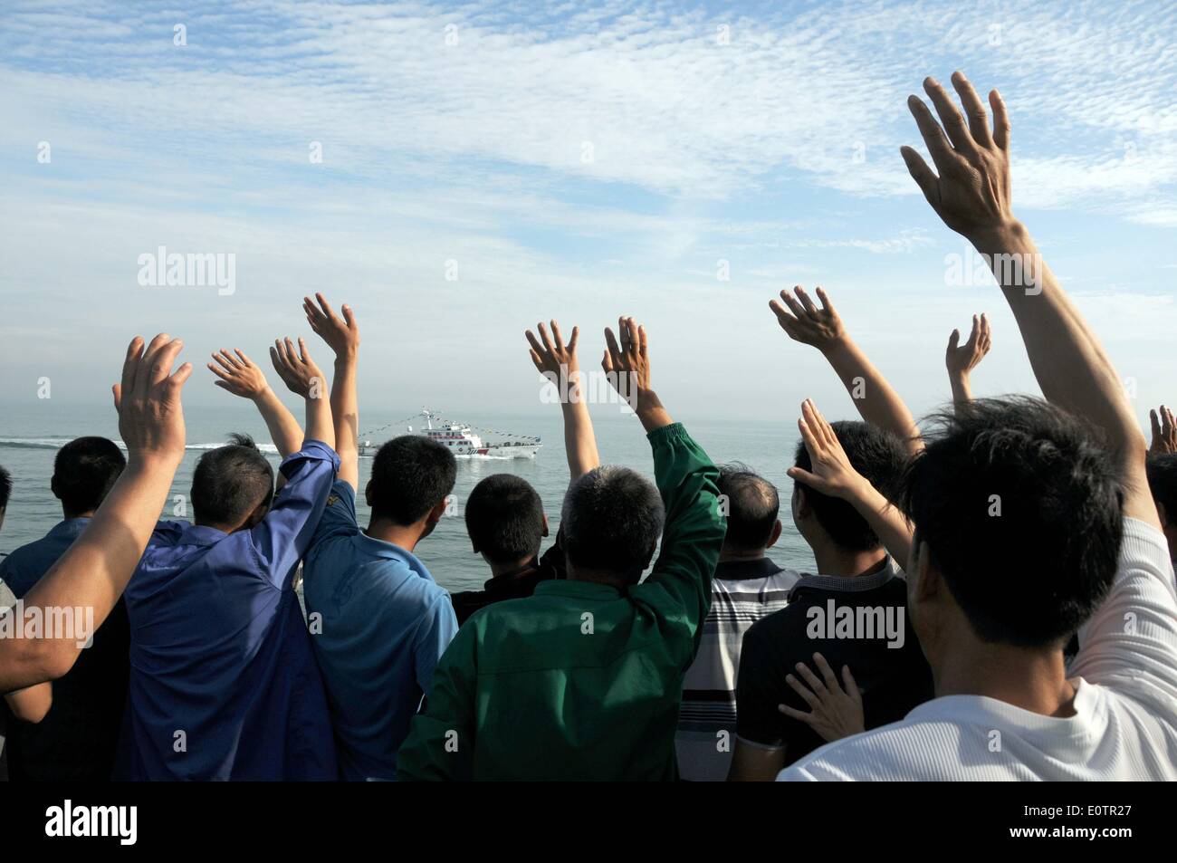(140520) -- A BORDO WUZHISHAN, 20 maggio 2014 (Xinhua) -- cittadini cinesi a bordo della nave passeggeri Wuzhishan onda per un cinese marine nave pattuglia, come la nave Wuzhishan capi di Haikou, capitale del sud della Cina di Hainan Provincia, 20 maggio 2014. Il primo gruppo di violenza-colpito lavoratori cinesi in Vietnam sono arrivati al porto di Haikou martedì mattina. Il governo cinese ha inviato quattro navi di domenica per evacuare riot-colpito lavoratori cinesi in Vietnam dove gravi atti di violenza di targeting le società straniere dal maggio 13 ha lasciato due cittadini cinesi morti e più di 100 altri feriti. Foto Stock