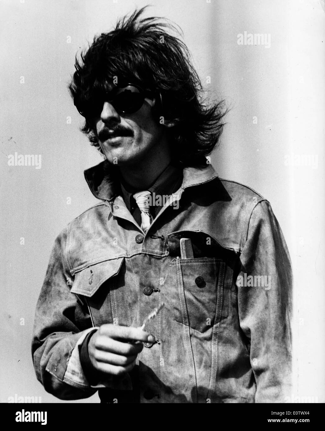 Ritratto di George Harrison in una camicia di jeans e occhiali da sole Foto Stock