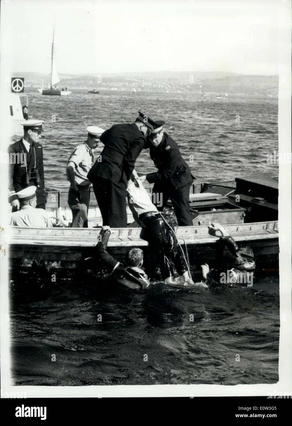 22 maggio 1961 - Canoe Anti-Polaris ''Commandos'' - rigondati dal lato delle navi: La Marina degli Stati Uniti è entrata in azione ieri con manichette antincendio - l'acqua di sei getti a bordo della nave missilistica Polaris ''Proteus'' ha battuto un ''Commando'''' raid da dimostranti anti anti anti-nucleari in canze. I dimostranti cercano di salire sulla catena di ancoraggio e sui falchi. Phot mostra la polizia trascinare uno dei dimostranti fuori dall'acqua in un lancio - dopo il hosing-down da manichette antincendio - al Loch Santo. Foto Stock