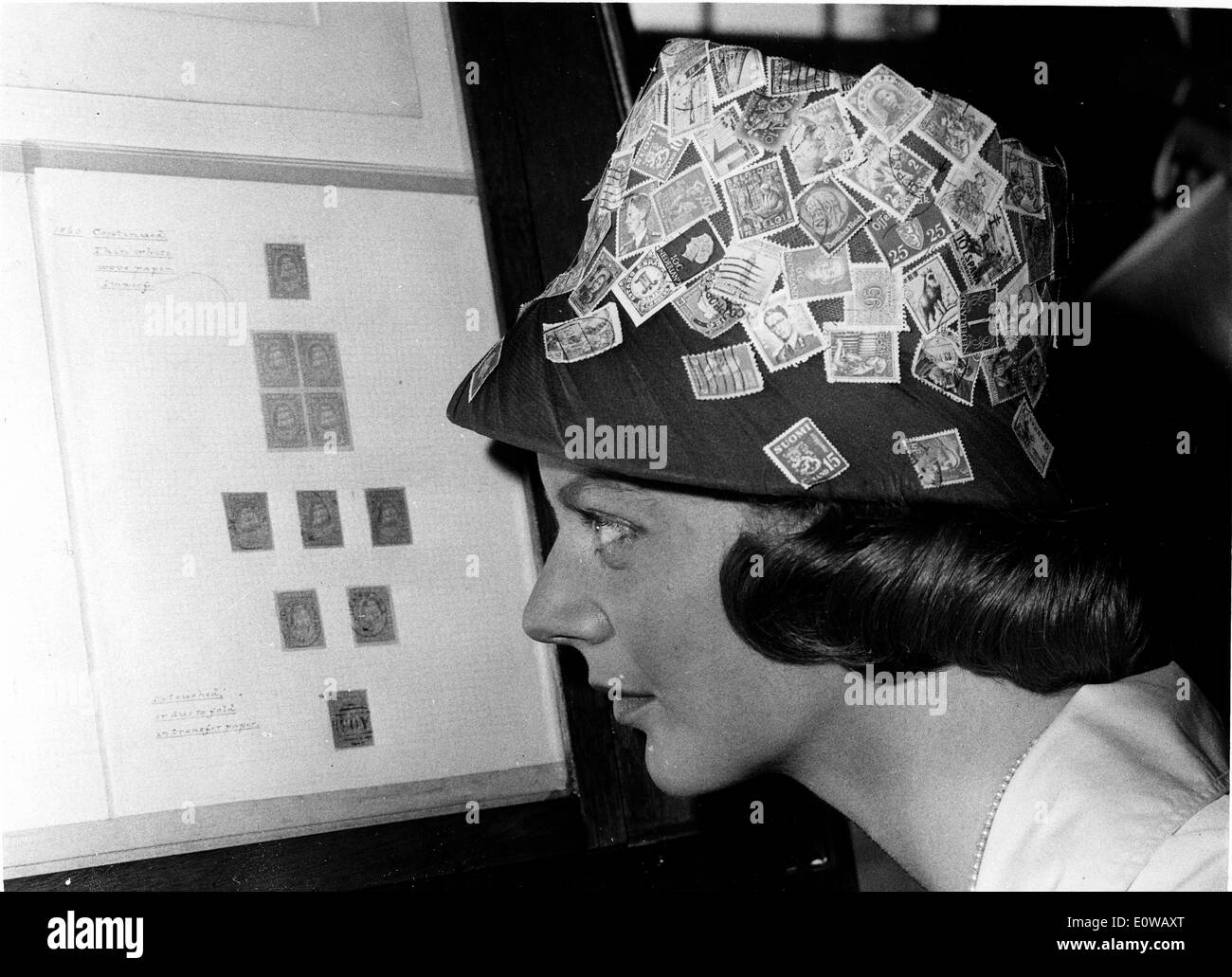 Modello indossando un cappello coperto con una varietà di francobolli Foto Stock