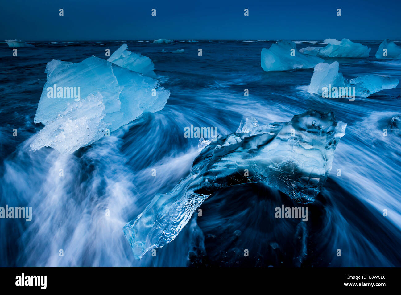 I cristalli di ghiaccio su una spiaggia nera di essere lambite dal mare, Jökulsárlón laguna glaciale, ghiacciaio Vatnajökull, Austurland Foto Stock
