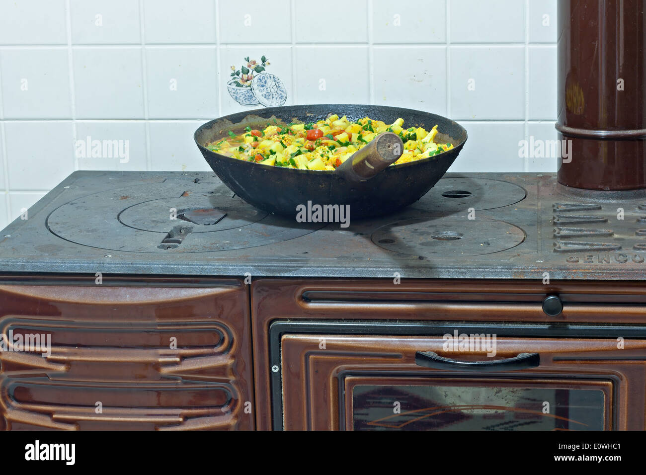 La cottura di un piatto di verdure su legno bruciando ghisa forno Foto Stock