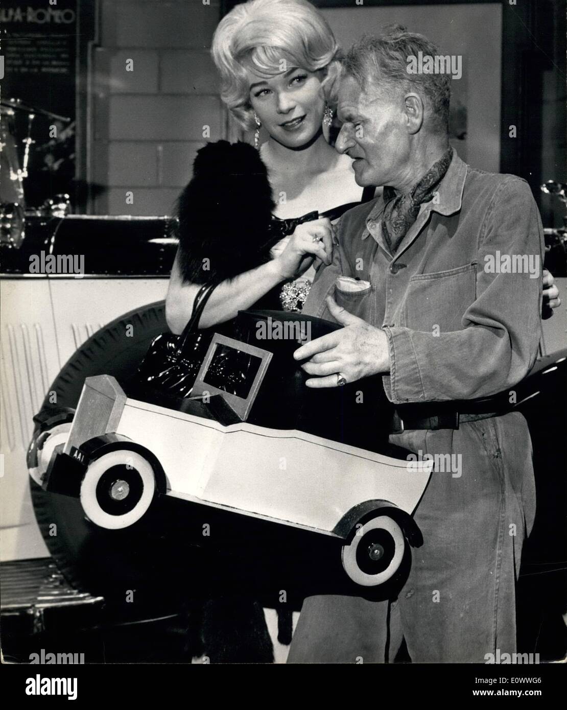 Lug. 07, 1964 - Shirley MaClaine playdirectors parte di un gangster's moll in una nuova pellicola britannica: American film star Shirley MaClaine era presso gli studi di Elstree riprese la parte di un gangster di ''moll'' per la nuova pellicola britannica ''Il Giallo Rolls Royce''. George C. Scott svolge il ruolo di un gangster. Mostra fotografica di Shirley MaClaine presenta Anthony Asquith, direttore,con uno sgabello realizzato come una replica del giallo Rolls Royce. Anthony odia seduti su sedie, preferisce uno sgabello durante le riprese, così il cast ha avuto questo modello appositamente realizzati per lui. Foto Stock