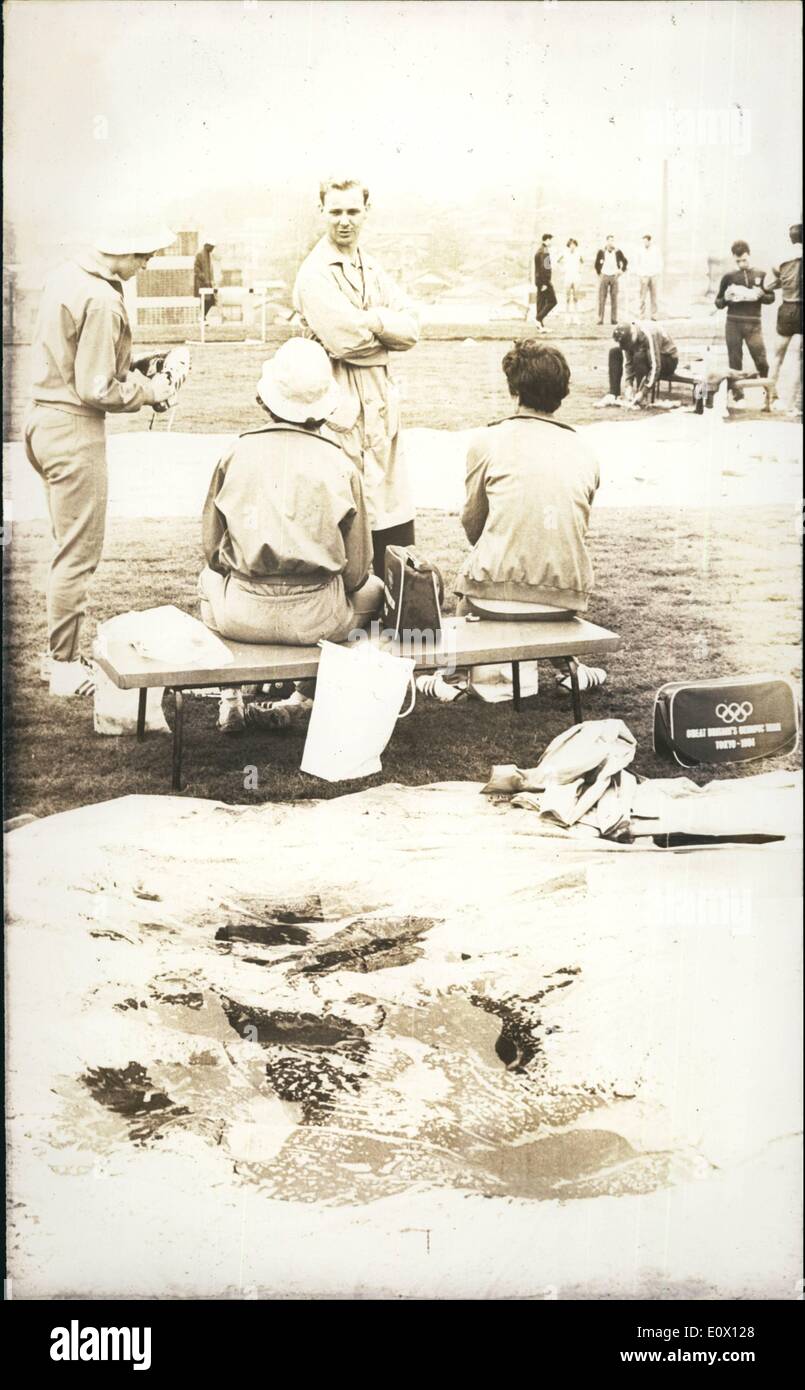 Ottobre 10, 1964 - Formazione allagata via.: teli in plastica fissati sulla formazione via del villaggio olimpico di provare e proteggerlo dalla pioggia che ha allagato i binari. Quattro membri della Gran Bretagna;s team olimpico di discutere la possibilità di fare un po' di allenamento sul imbevuto via. Foto Stock