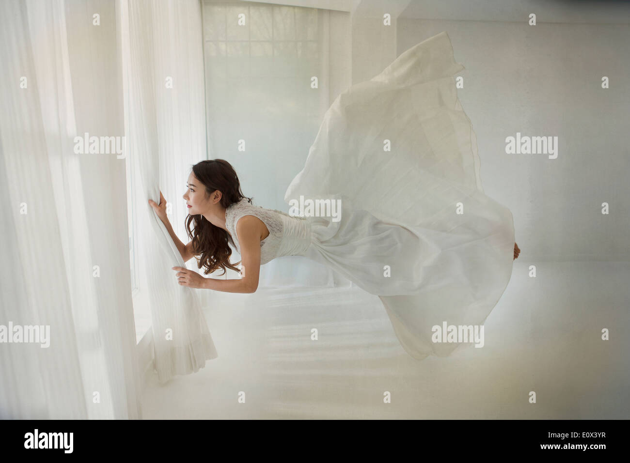 Una donna floating orizzontalmente in una camera vicino alla finestra Foto Stock