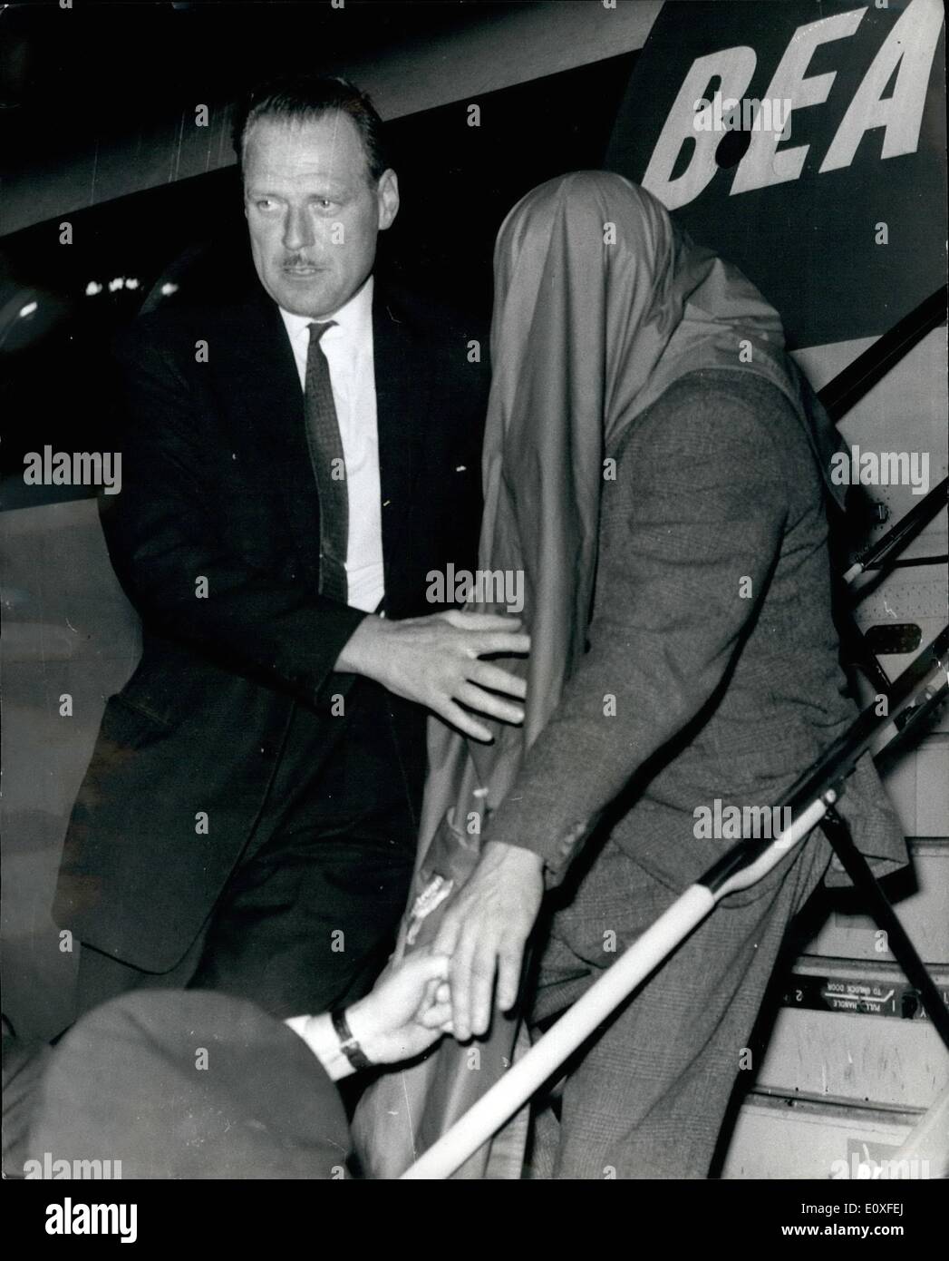 Agosto 08, 1966 - John Duddy volato a Londra arresto in Glasgow: John Duddy, voluto per un interrogatorio in connessione con le riprese di tre poliziotti di Londra lo scorso Venerdì era volato a Londra la scorsa notte dopo essere stato arrestato in Glasgow. Quaranta poliziotti erano in attesa all'Aeroporto di Londra. Duddy è stata azionata per Shepherd's Bush stazione di polizia in un convoglio di orecchie e i cicli del motore. Mostra immagine: John Duddy, il capo coperto da una pioggiamangiare, arriva all'Aeroporto di Londra la scorsa notte da Glasgow. Foto Stock