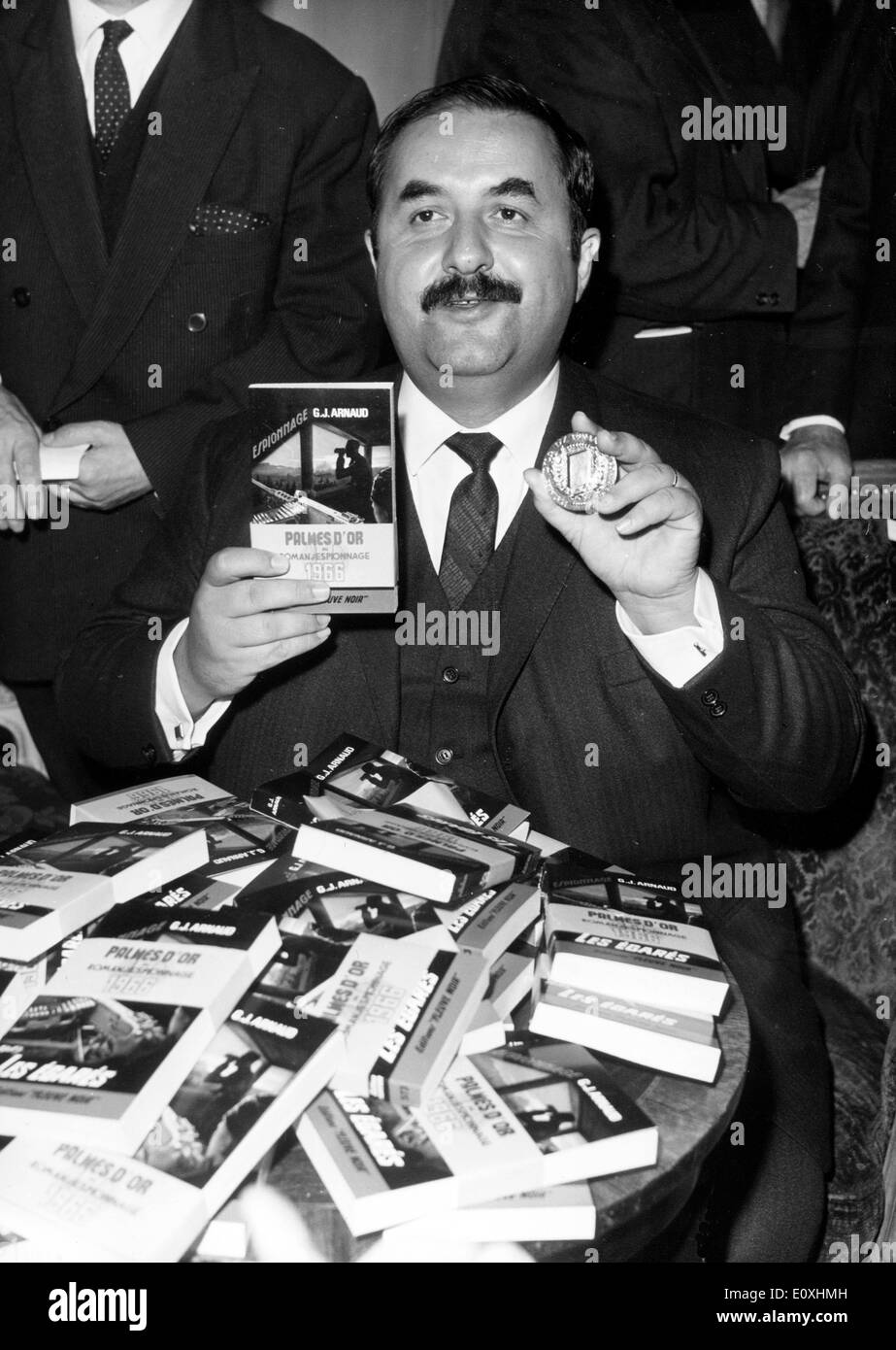 Oct 26, 1966; Paris, Francia; il premio annuale della "Palmes D'o' (Golden Palm) per il miglior romanzo di spionaggio dell'anno è andato a J. Arnaud per il suo libro 'Les Egares' (quelli persi). La foto mostra GEORGES J. ARNAUD che mostra il suo libro e medaglia. Foto Stock