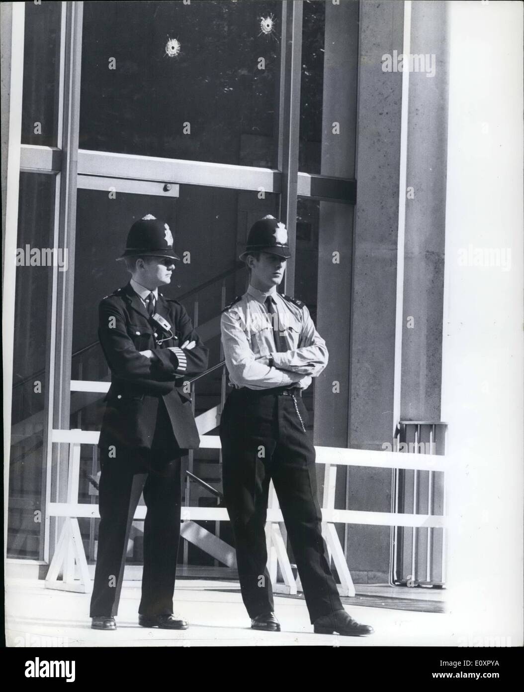 Agosto 08, 1967 - Machine Gun attacco all ambasciata degli Stati Uniti a Londra. Un massiccio caccia era stato lanciato oggi per i banditi che la scorsa notte spruzzato l ambasciata americana con la mitragliatrice proiettili dal passaggio di un auto. I proiettili trafitto il finestrino e la lastra di vetro e porte di uffici consolari in Grosvernor superiore Street. La foto mostra due poliziotti di guardia al di fuori delle sedi consolari ala in Upper Grosvenor Street questa mattina. Al di sopra di loro può essere visto due dei fori di proiettile, realizzata mediante i banditi. Foto Stock