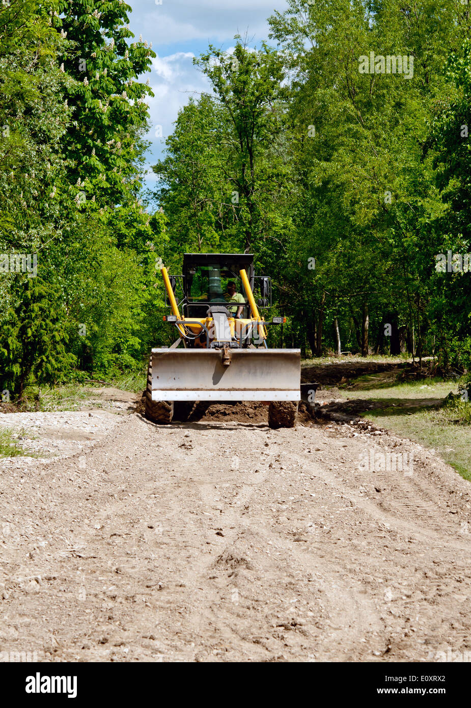 Grande giallo motolivellatrice resurfacing una stretta strada rurale Foto Stock