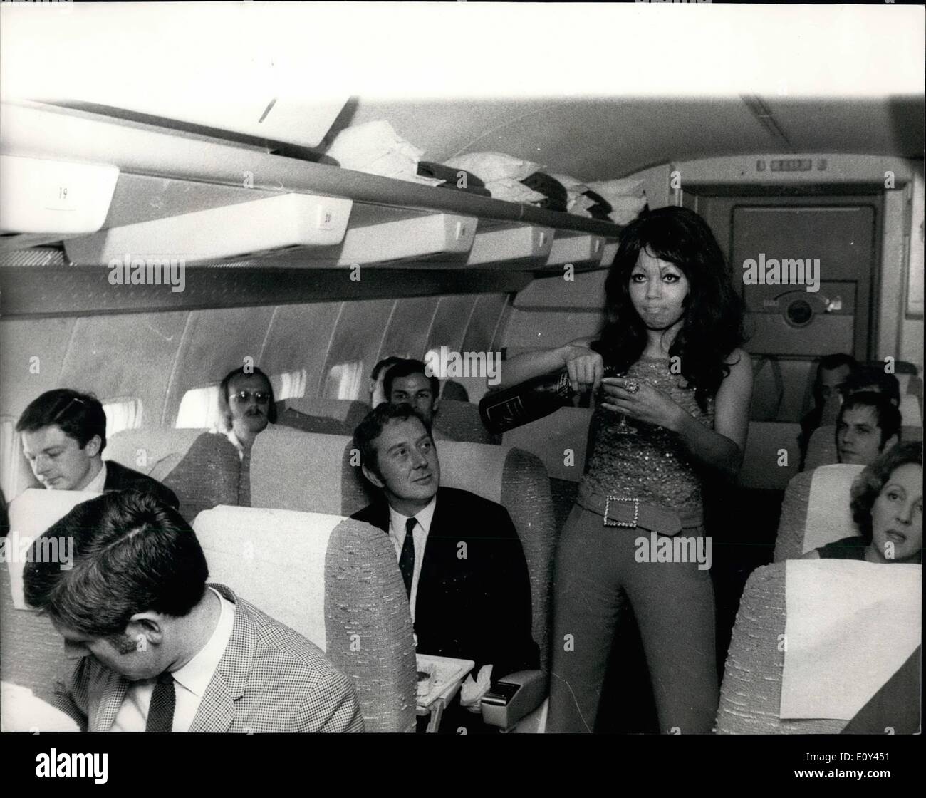 Lug. 07, 1968 - il volo aereo per promuovere il nuovo record di Chris Rayburn.: per promuovere la nuova registrazione da 23 anni nato a Chicago Chris Rayburn, ha effettuato un volo speciale dall'aeroporto di Gatwick oggi in tutto il sud e la costa orientale dell'Inghilterra, in un piano noleggiate dalla casa discografica, MGM, durante i quali il record, chiamato ''biglietto di sola andata'' è stato giocato. Chris Rayburn indossava un rosso pantaloni adatti di Clive. Mostra fotografica di Chris Rayburn versa dello champagne per passeggeri nel corso del volo. Foto Stock