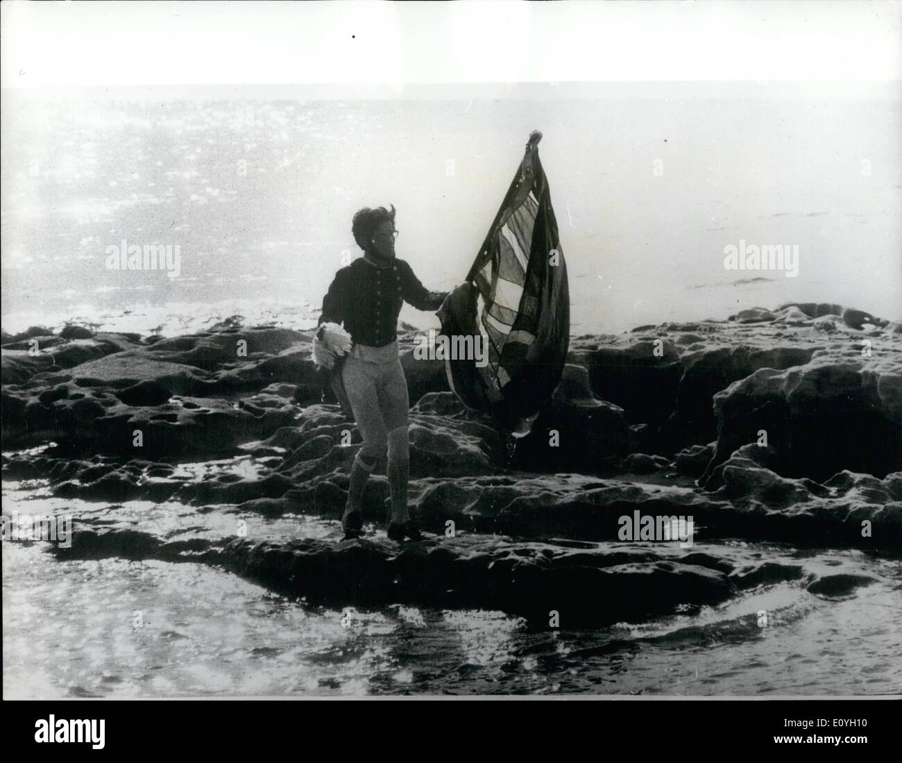 Maggio 05, 1970 - Queen orologi Re-Enactment del capitano Cook's Landing: come la famiglia reale atteso per guardare una rievocazione della Captain Cook's Landing in botanica vicino a Sydney, Australia burloni in un motore fuoribordo barca ha rubato la mostra. Vestito in costume due studenti hanno gareggiato per la riva portando un Unione Jack, inseguita dalla polizia lancia, e piantato la loro bandiera prima dell'atterraggio ufficiale potrebbe ottenere in modo. L'incidente è stato guardato da membri della famiglia reale. La foto mostra lo studente ''cuocere'' circa di piantare la bandiera su una roccia nella baia - prima che il funzionario ''Captain Cook'' atterraggio. Foto Stock