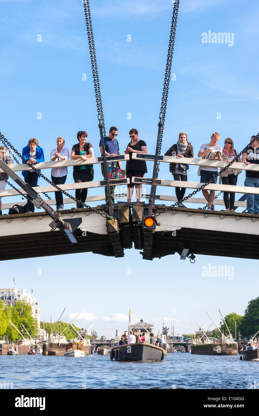 Amsterdam Magere Brug, Skinny Bridge, con persone i turisti i visitatori a guardare le barche sul fiume Amstel. Visto dal Canal Cruise. Foto Stock