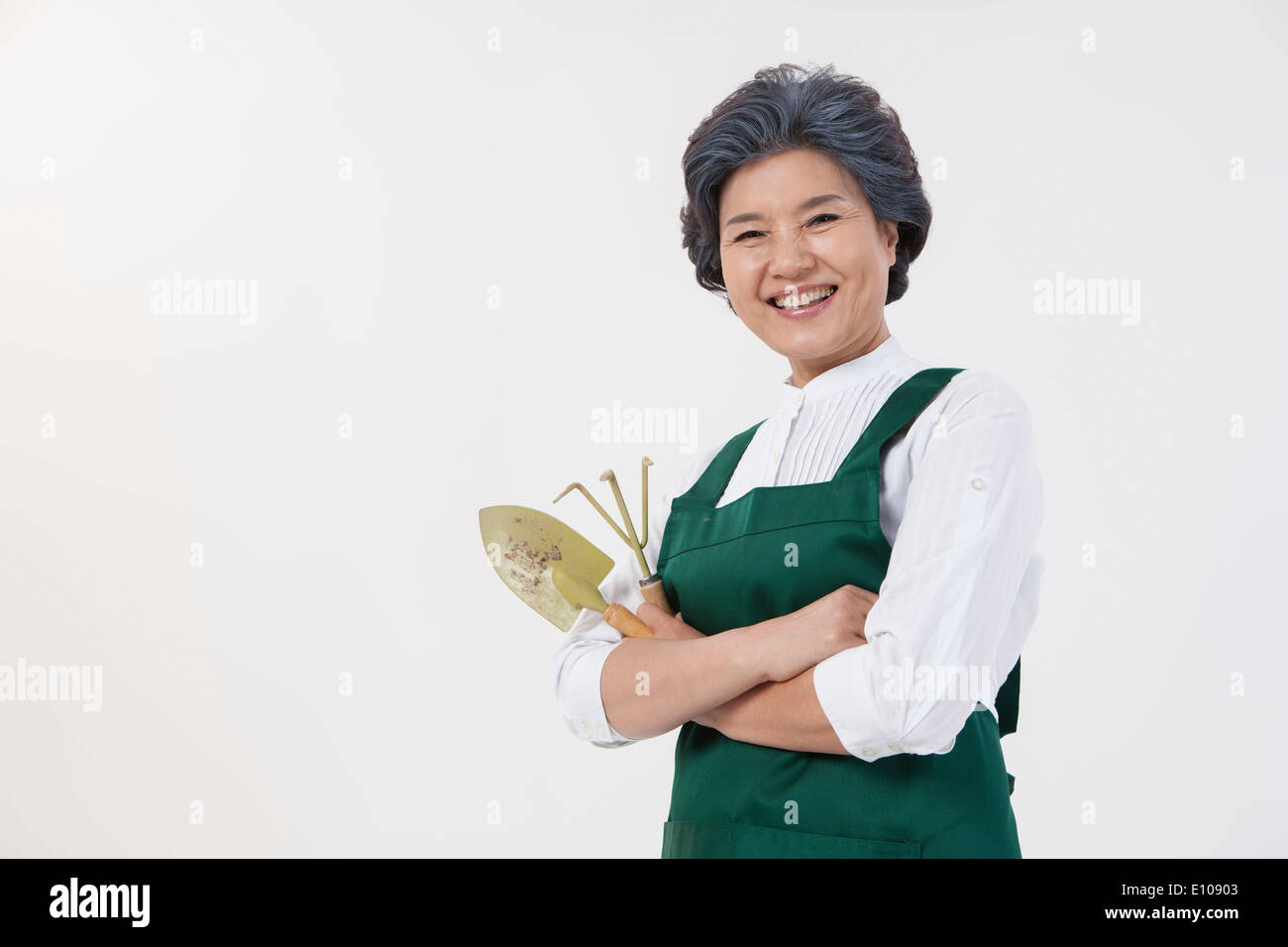 Una donna anziana con un grembiule azienda utensili da giardinaggio Foto Stock