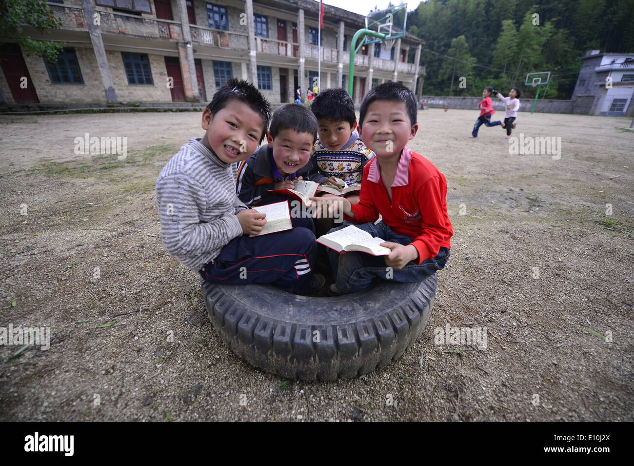 (140521) -- WANZAI COUNTY, 21 maggio 2014 (Xinhua) -- quattro studenti della Cram in un pneumatico dei rifiuti come essi scorri i dizionari dato dai donatori pubblici Liyuan presso la scuola elementare nel villaggio Xikeng sotto Wanzai contea di Yichun, Cina orientale della provincia di Jiangxi, 20 maggio 2014. La mancanza di insegnanti qualificati è stata un problema onnipresente che preoccupa molte scuole elementari in Cina rurale. Le autorità competenti per l'istruzione di Wanzai County hanno lanciato un cinque anni di programma di formazione del corpo docente nel 2014 per affrontare la domanda per gli insegnanti nella contea di aree rurali. Ogni anno il programma riceveranno 30 junior alta richiedente Foto Stock