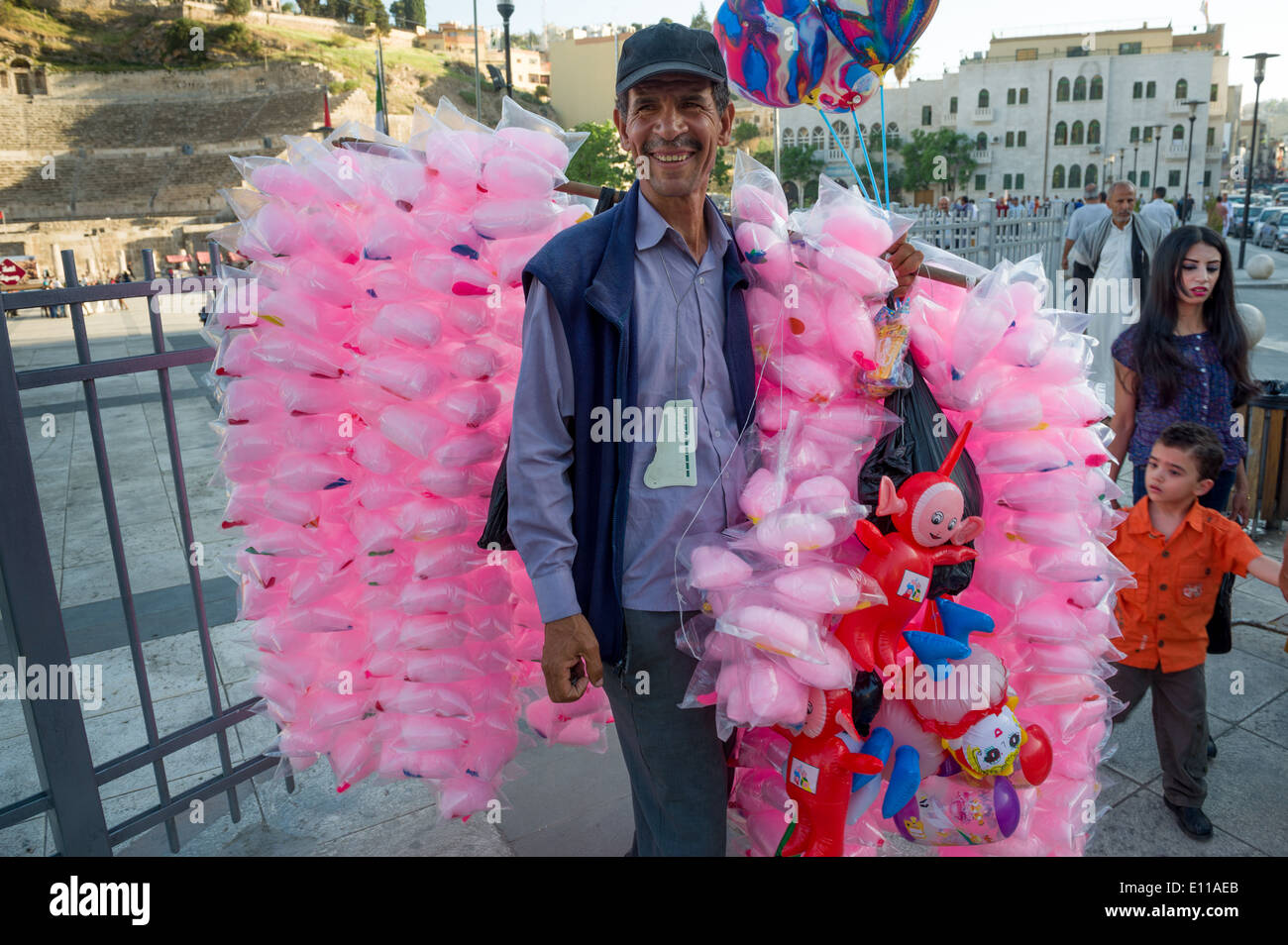 Uomo giordani la vendita di caramelle rosa-filo interdentale nella vivace piazza antistante il teatro romano, Amman, Giordania Foto Stock
