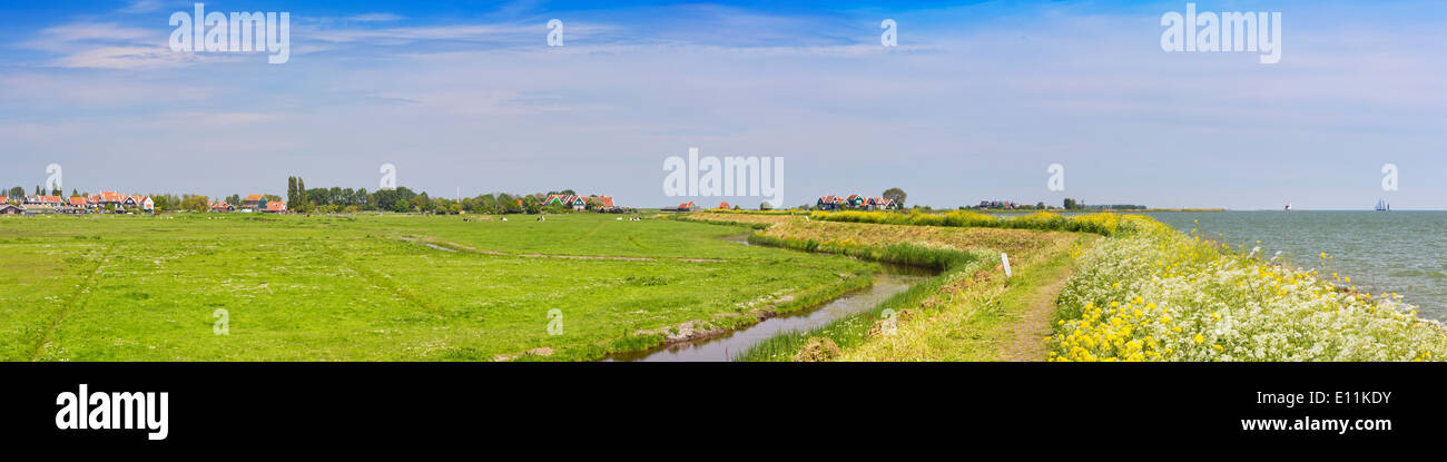 Una diga attraverso il tipico paesaggio Olandese su una luminosa e soleggiata giornata di primavera Foto Stock