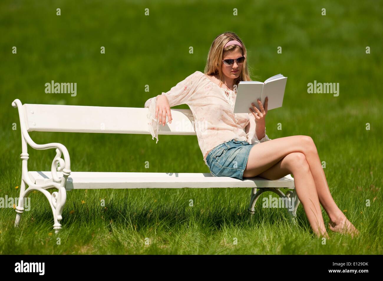 Apr. 22, 2009 - 22 Aprile 2009 - giovane donna con occhiali da sole seduta sul banco di bianco; shallow DOF Foto Stock