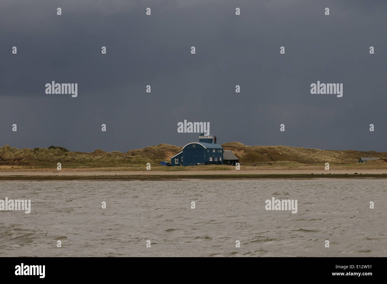 La vecchia imbarcazione di salvataggio House station e dune di sabbia sul punto Blakeney contro un cielo scuro. Foto Stock