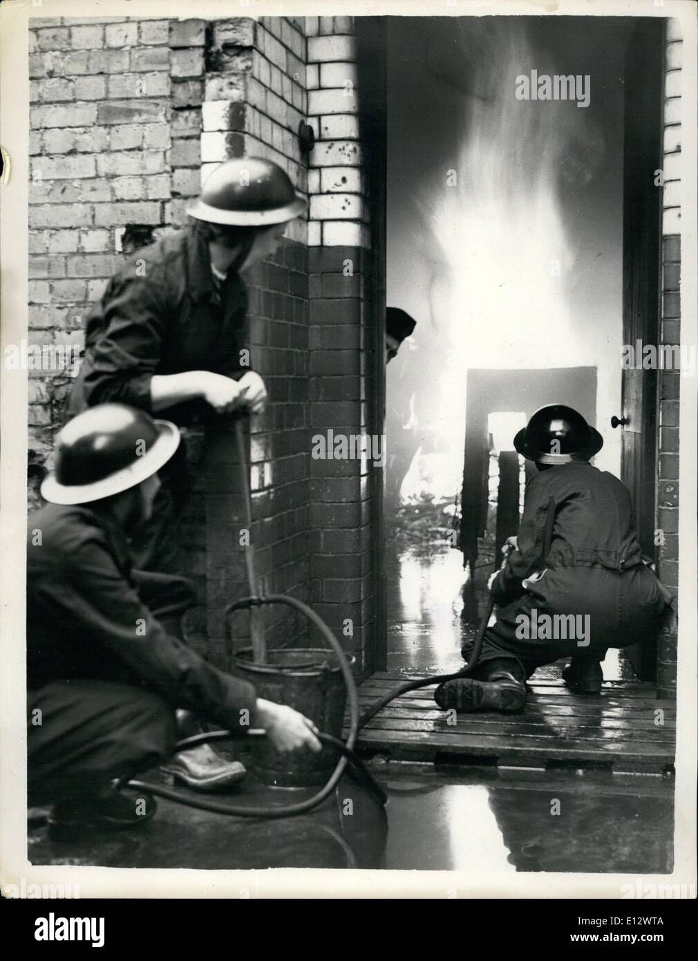 Febbraio 26, 2012 - Lotta antincendio pratica su di un sito bombardato. Banca di Difesa Civile unità in formazione. In risposta all'appello del governo per il business case per formare la propria unità di difesa civile sig. A.R. Newman ha formato uno presso la Città sede della banca di Londra e il Sud America. L'unità può spesso essere visto nella formazione sui siti bombardati intorno Lothbury. Keystone Foto Mostra: Tre membri delle donne del team antincendio in pratica su di un sito bombardato. Essi sono Miss Alice Benbow (riproduzione del tubo flessibile); Sheila Gunn il funzionamento della pompa e Phyllis Adamthwaite mantenendo la fornitura di acqua. Foto Stock