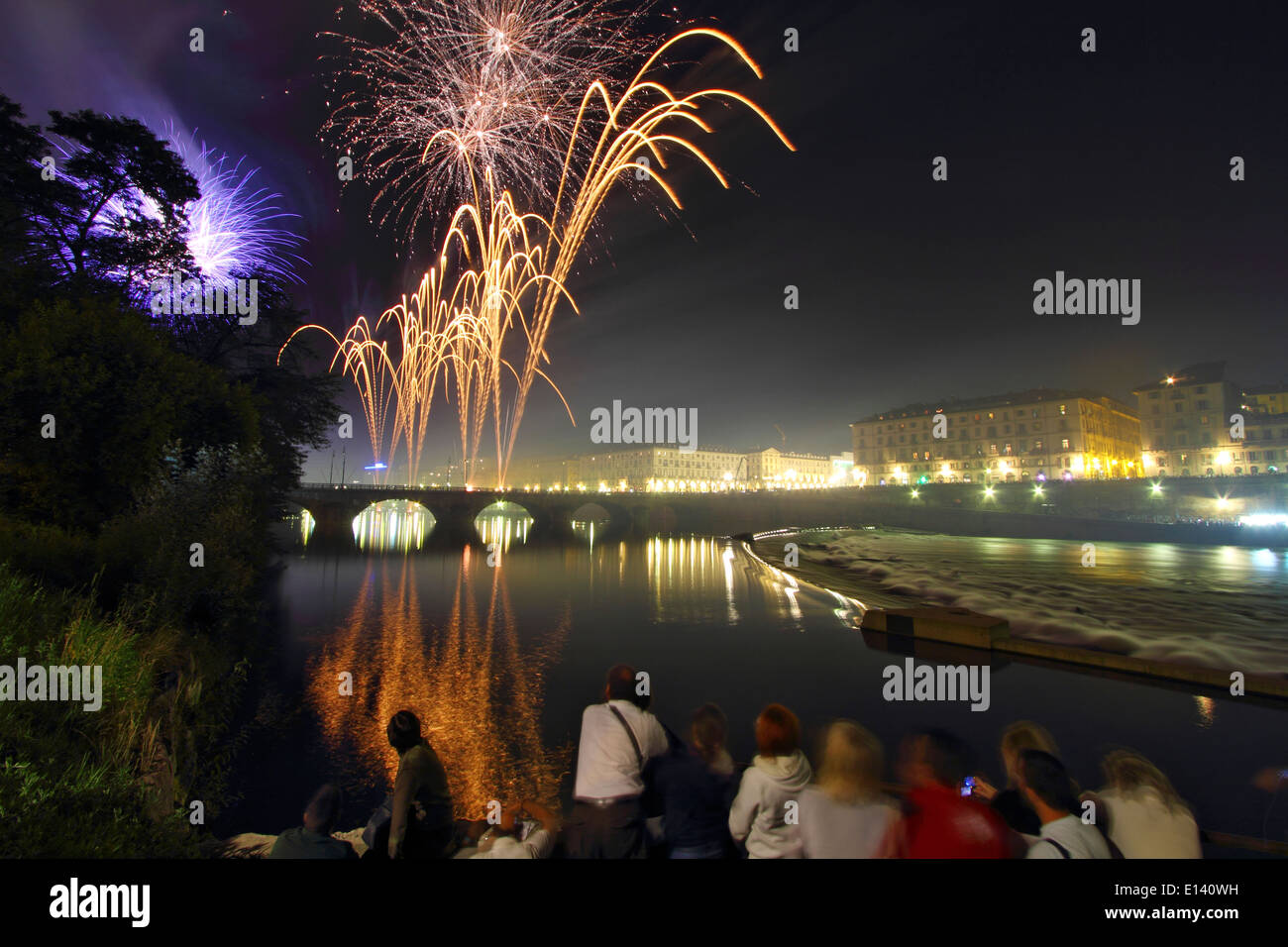 La gente a guardare lo spettacolo di fuochi artificiali dalle rive del fiume Po a Torino durante la Saint John's celebrazioni. Foto Stock