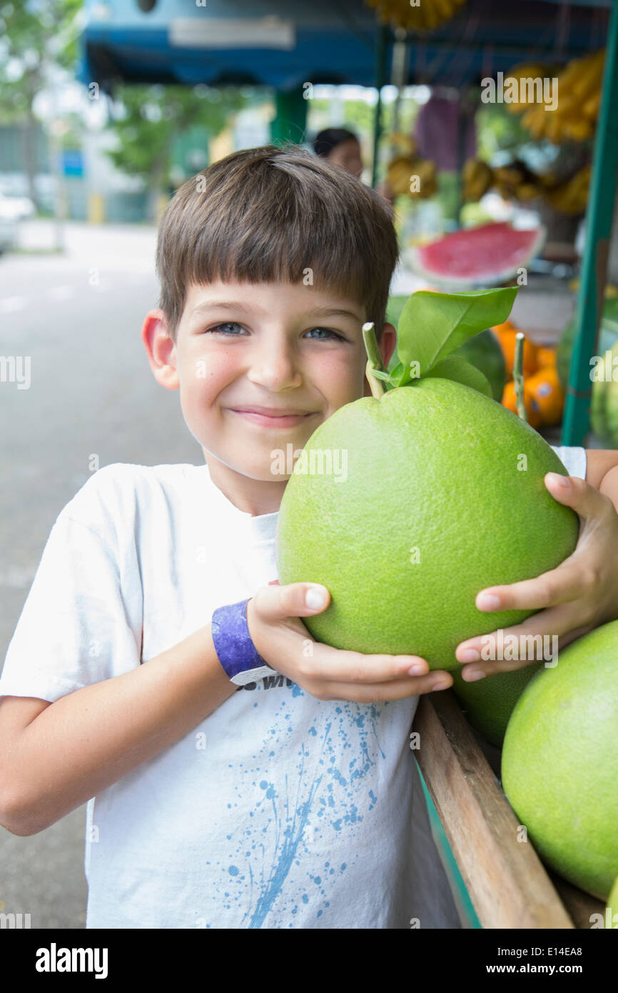 Ragazzo caucasico azienda frutti di grandi dimensioni sul mercato Foto Stock