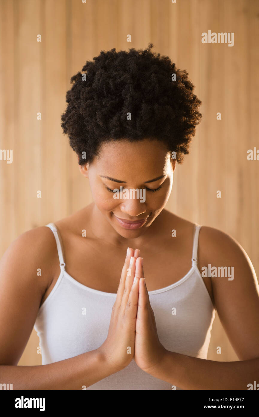 Close up di serena donna nera con le mani in posizione di preghiera Foto Stock