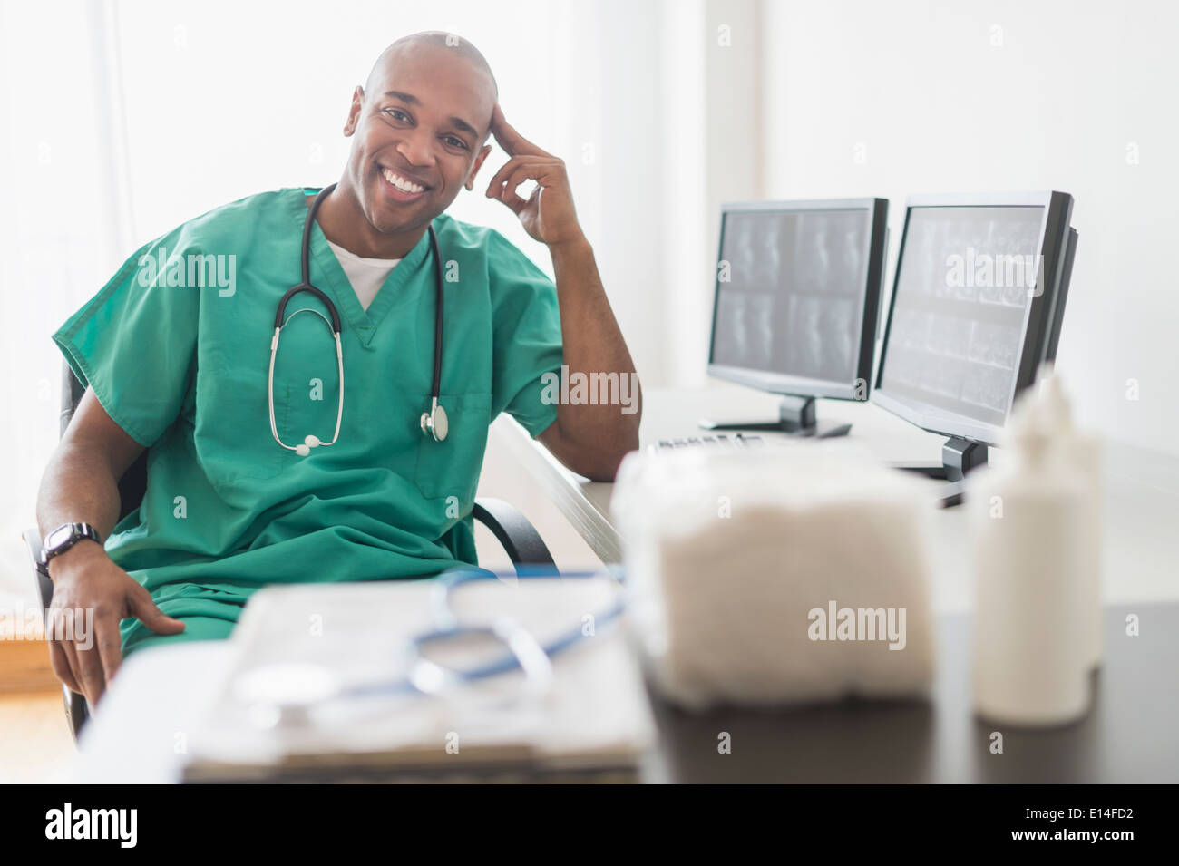 Medico nero sorridente al computer in ufficio Foto Stock