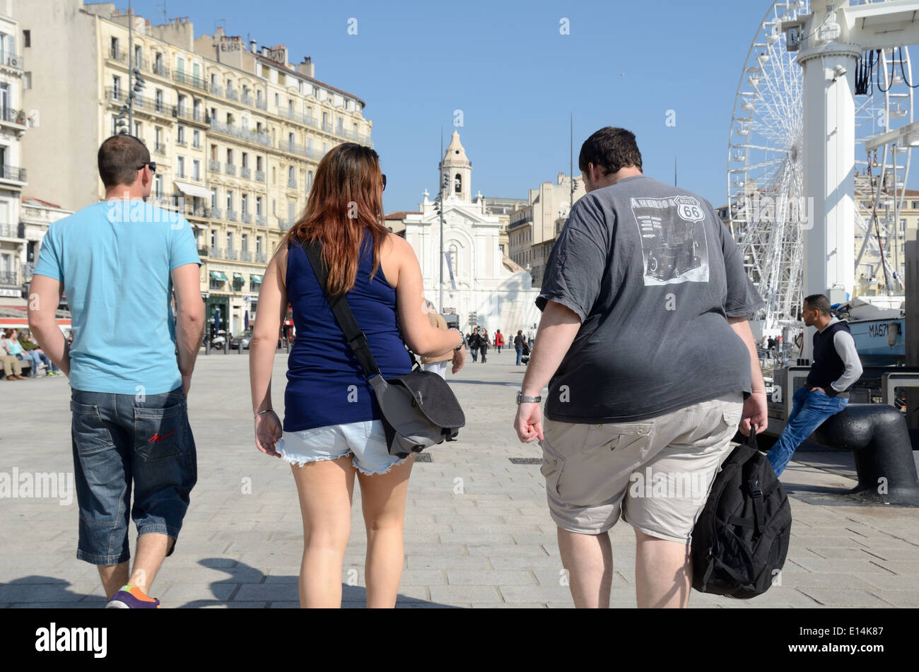 Tre giovani adulti compresi i grandi obesi Fat Man Walking sul Quai du Port Porto Vecchio Marsiglia Francia Foto Stock