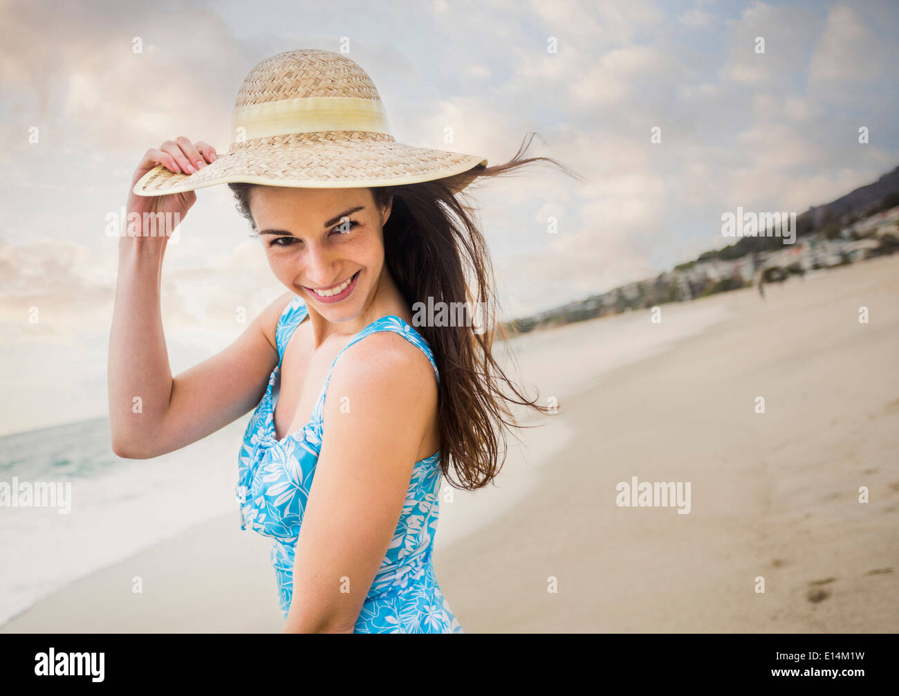 La donna caucasica indossando cappello di paglia sulla spiaggia Foto Stock