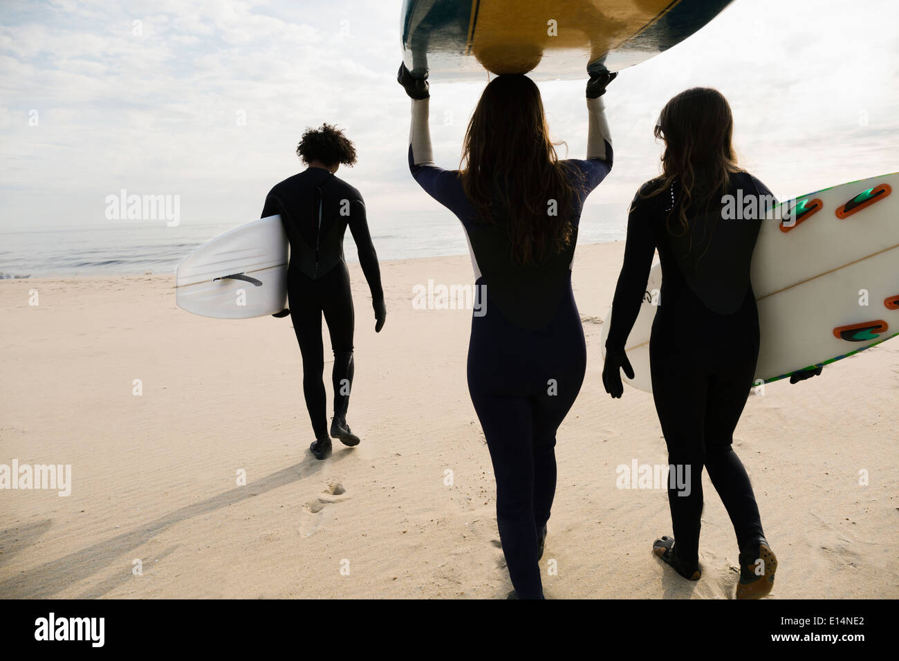 Surfers che trasportano tavole sulla spiaggia Foto Stock