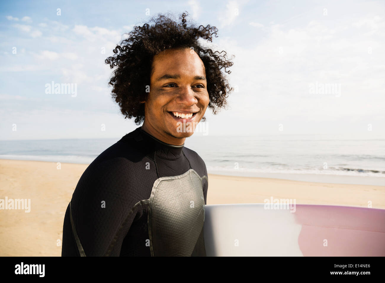 Razza mista surfer scheda portante sulla spiaggia Foto Stock