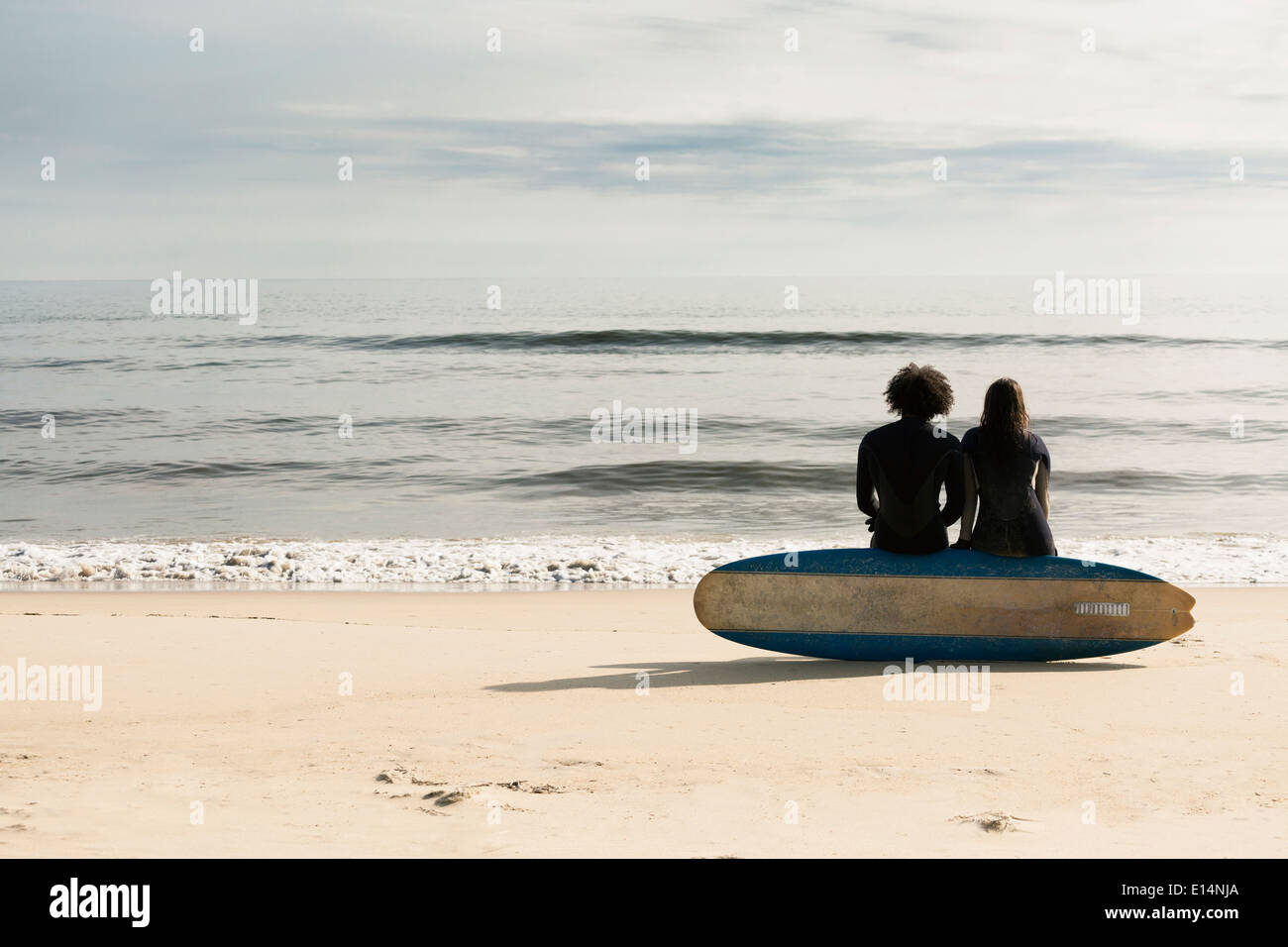 Surfers seduto a bordo sulla spiaggia Foto Stock