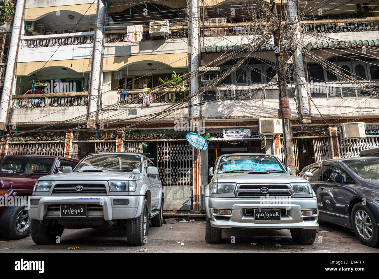 Veicoli parcheggiati davanti a un edificio residenziale, cavi aggrovigliati, linee di alimentazione, Yangon o Rangoon, Regione di Yangon, Myanmar Foto Stock