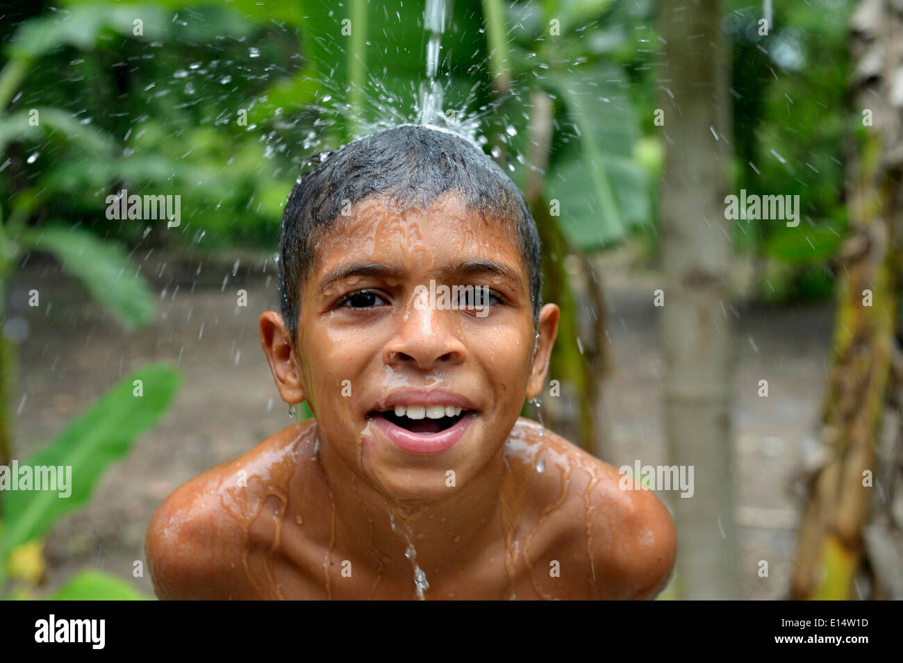 Ragazzo brasiliano tenendo la sua testa in un flusso di acqua e di ridere, progetto sociale per i bambini di strada, Maranguape, Ceará, Brasile Foto Stock