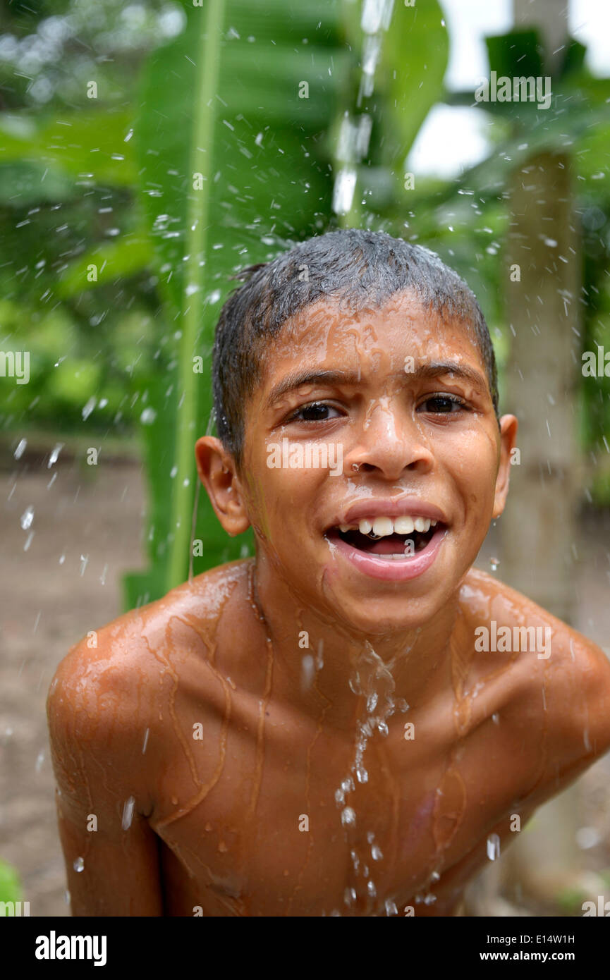 Ragazzo brasiliano tenendo la sua testa in un flusso di acqua e di ridere, progetto sociale per i bambini di strada, Maranguape, Ceará, Brasile Foto Stock
