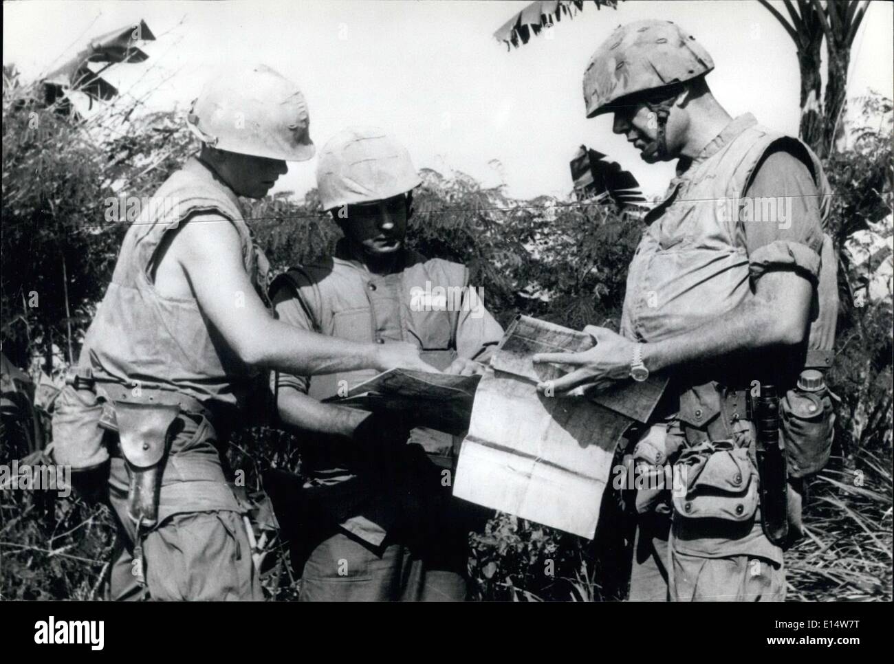 Apr. 18, 2012 - Conferenza nella giungla: tre ufficiali degli Stati Uniti controllare le proprie mappe in una radura della giungla durante una spinta nella boccola in cerca del Viet Cong. Gli ufficiali sono indossare i loro bulled-prova giacche. Foto Stock