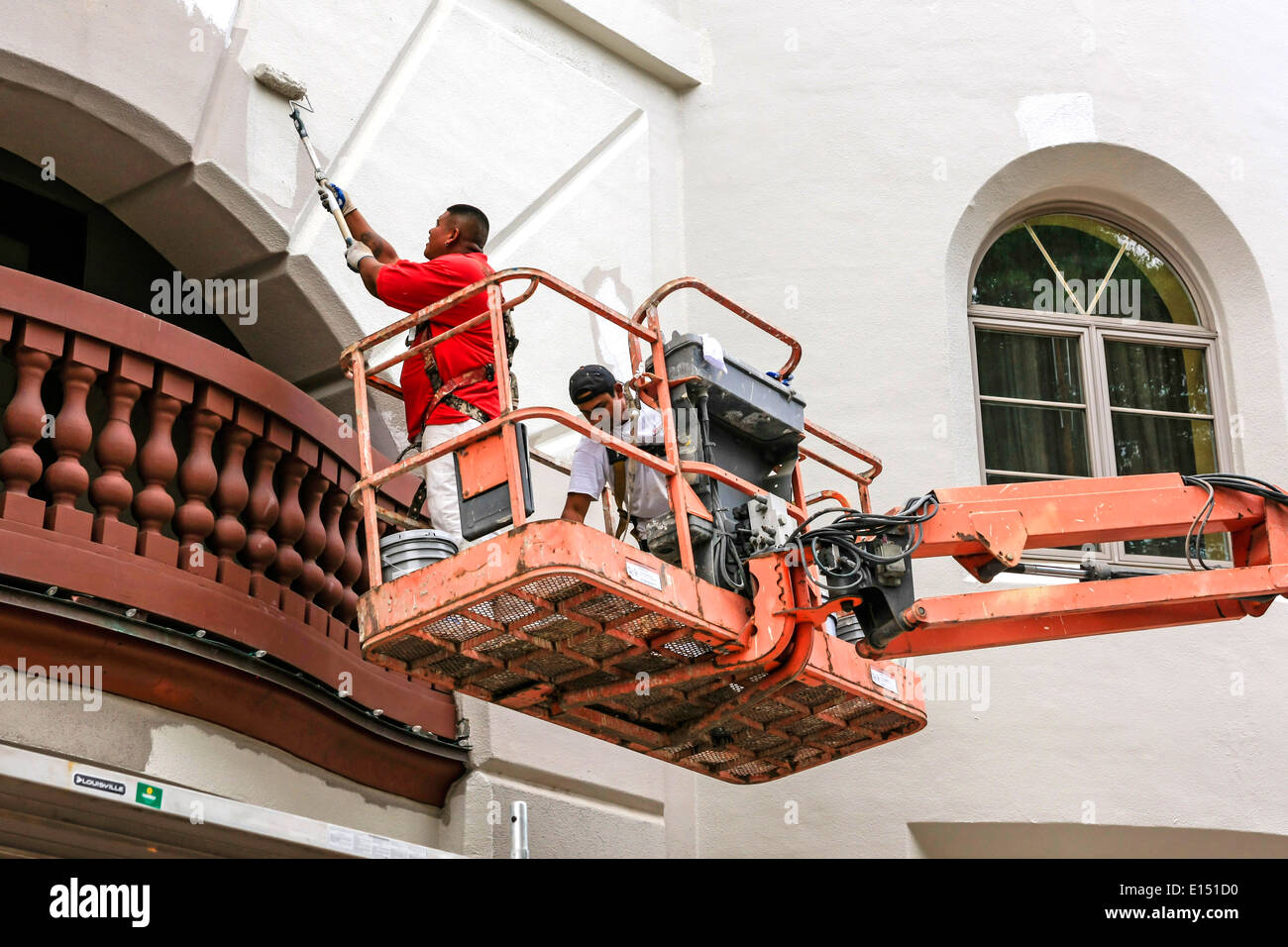 Pittori al lavoro utilizzando un cherry picker e rulli di vernice Foto Stock