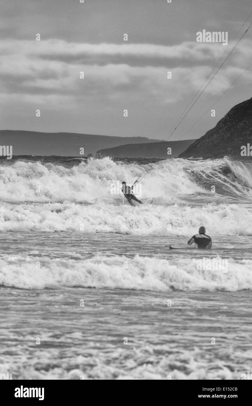 Un surfista e kite surfer insieme fuori dalla spiaggia di Hell's bocca Bay.. Il cielo è plumbeo e navigare in aumento come la marea si trasforma. Foto Stock