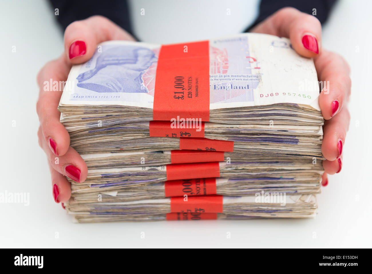 Una donna holding £1000 fasci di sterline. Foto Stock