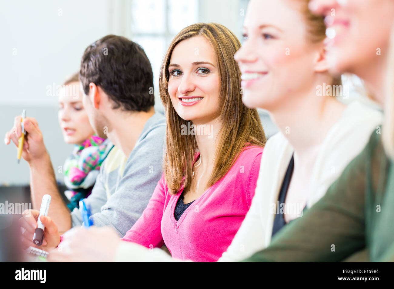 Studenti del college rendendo note di lezione in auditorium universitari Foto Stock