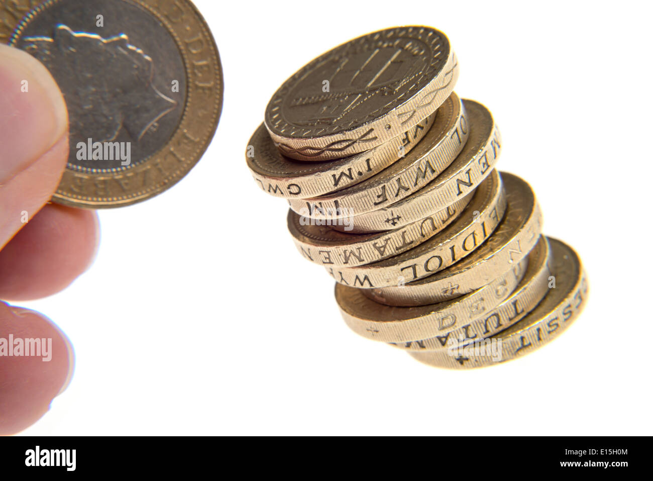 Pila di libbra di monete in euro con una mano che tiene un due pound coin Foto Stock