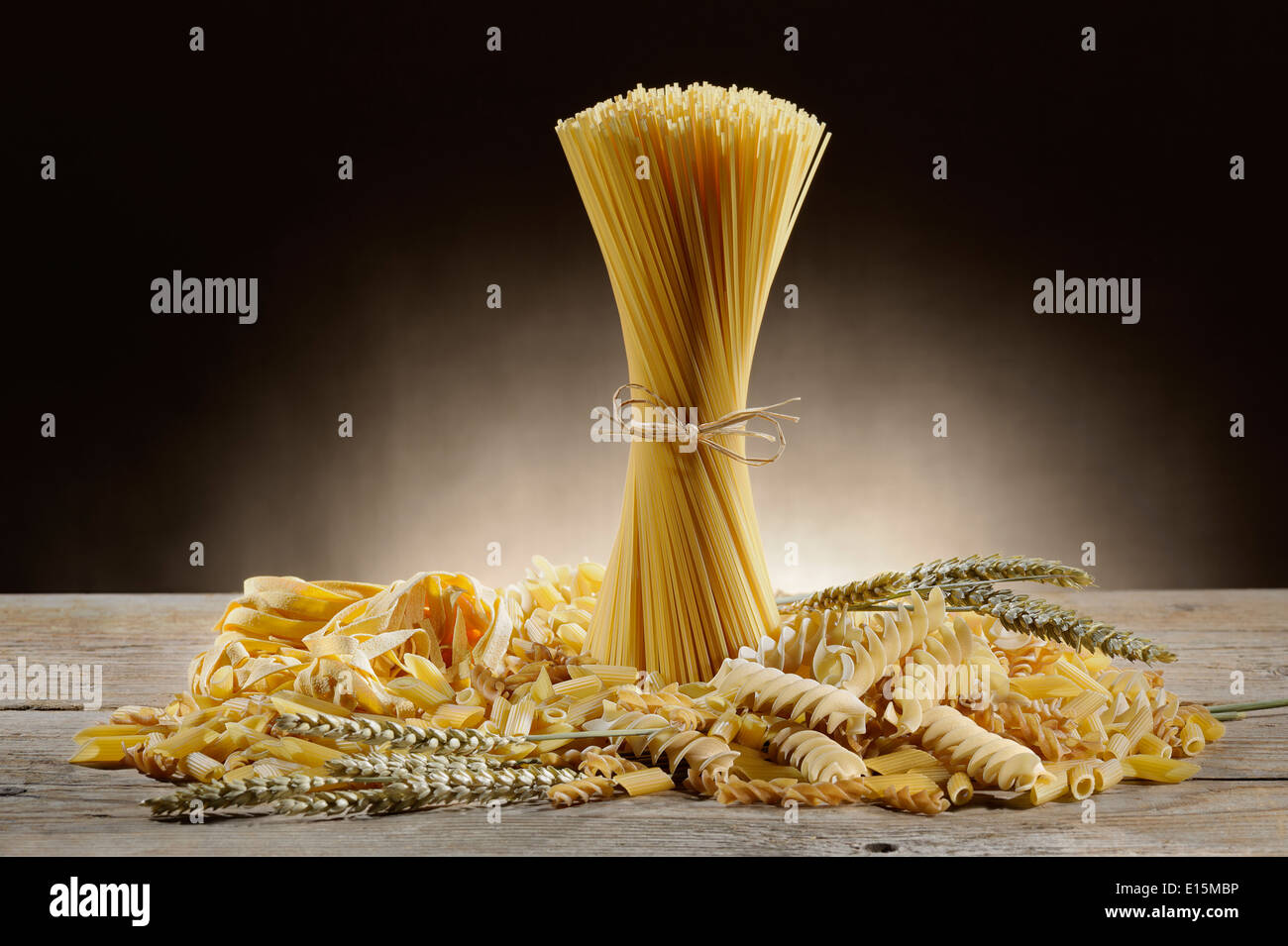 Varietà di pasta cruda sul tavolo di legno con spighe di grano Foto Stock