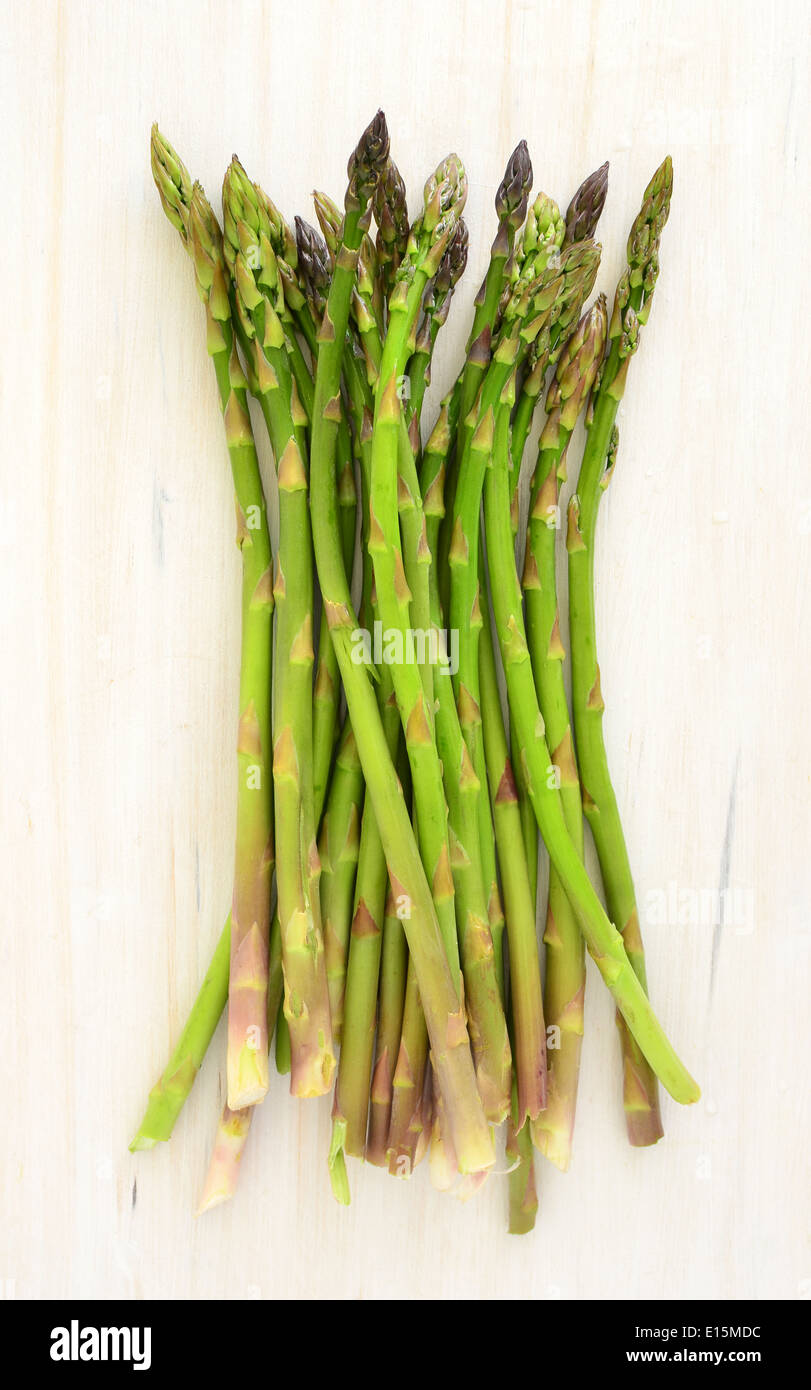 Giovani germogli di asparagi sul bianco rustico tagliere sfondo Foto Stock