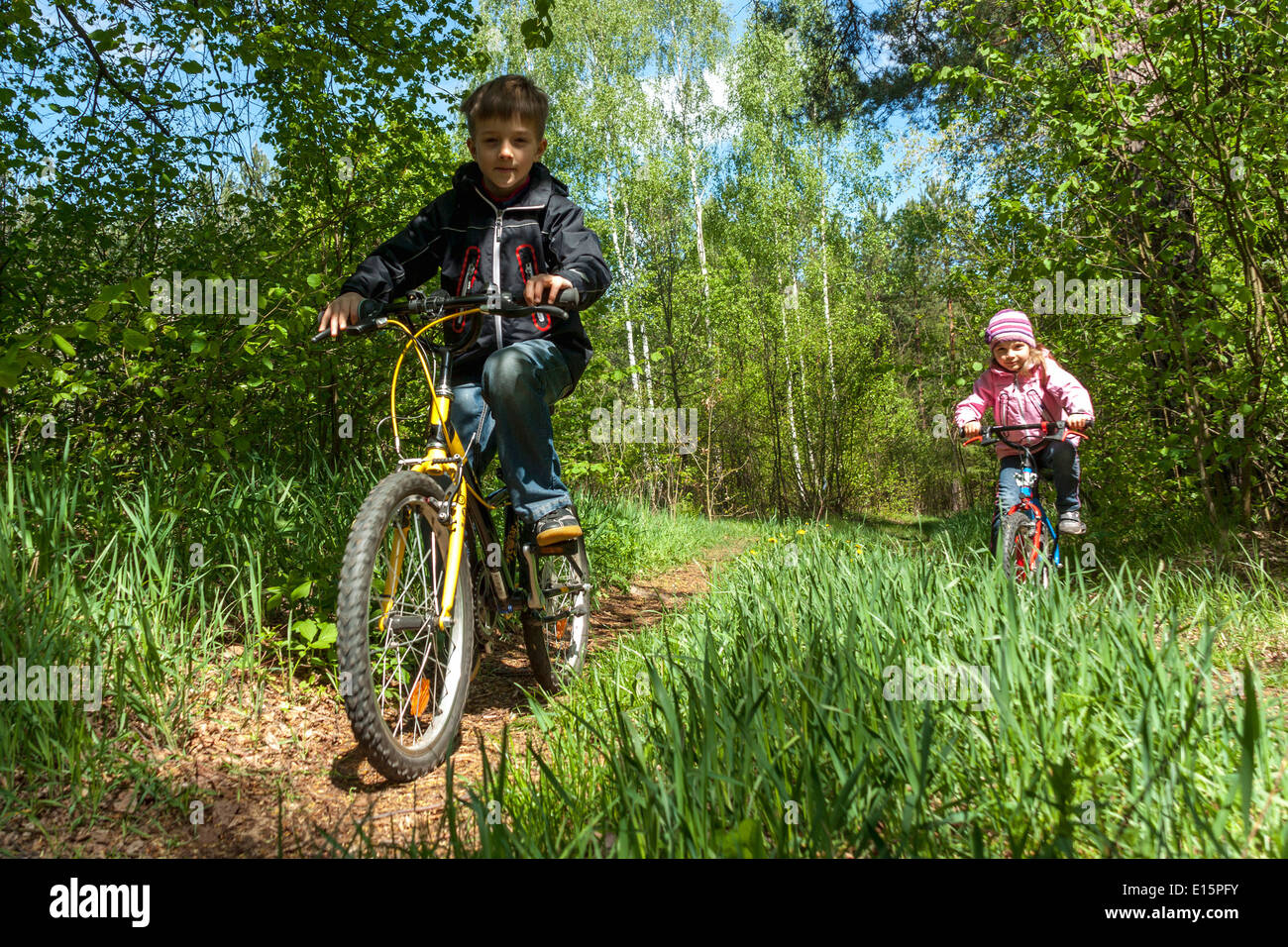Un ragazzo e una ragazza in sella la loro bicicletta in una foresta Foto Stock